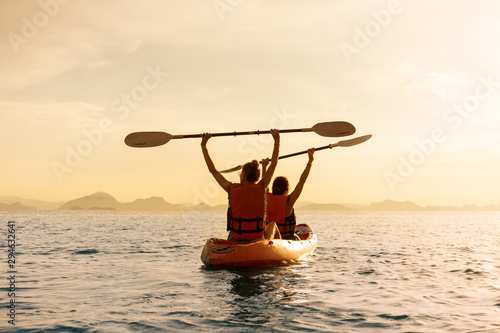 Couple kayaking together. Beautiful young couple kayaking on lake together and smiling at sunset photo