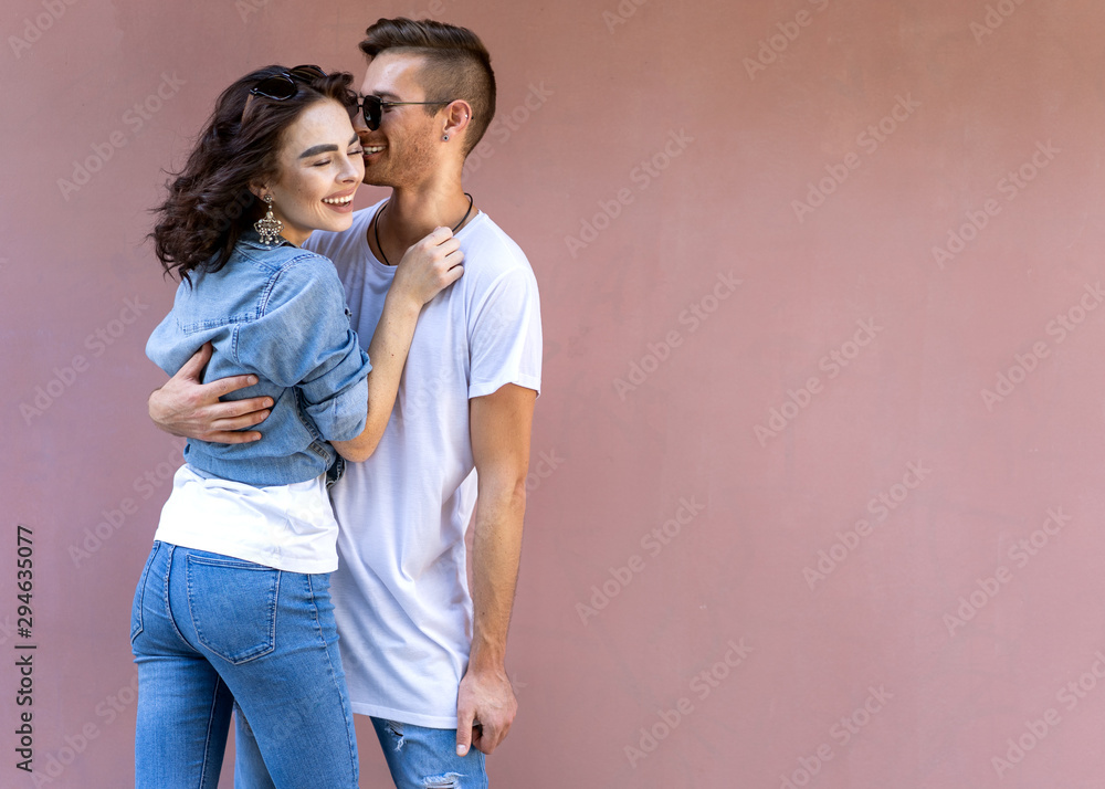 Naklejka premium fashion couple in sunglasses posing on pink wall