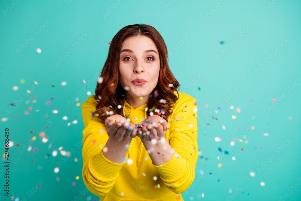 Photo of charming cute fascinating nice young girlfriend blowing confetti at you to show her festive mood with emotional face expression isolated over turquoise vivid color background - obrazy, fototapety, plakaty 
