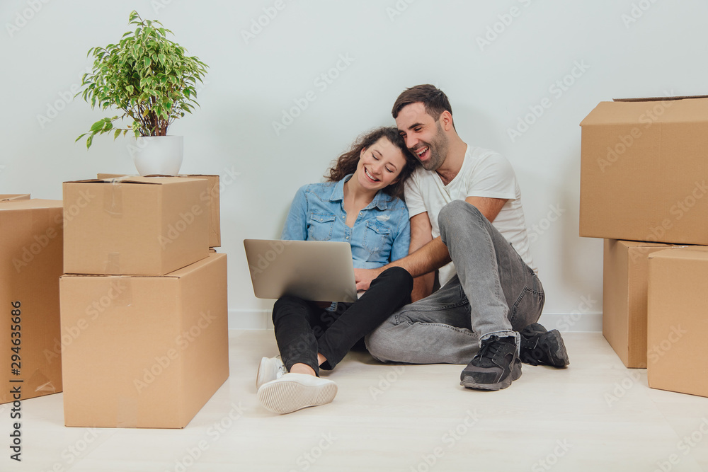 Young couple with laptop in the apartment, sitting on the floor, surfing in the internet, looking for new furniture. Young couple with laptop in the apartment, sitting on the floor, surfing in the internet, looking for new furniture.