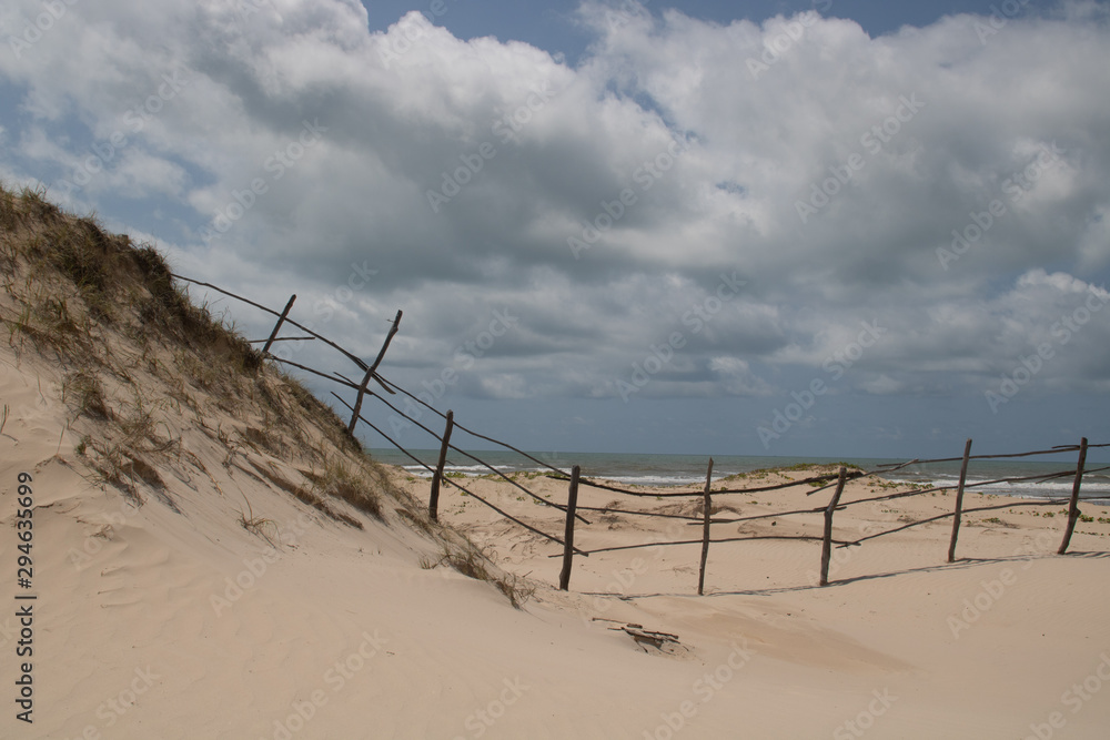 sand dunes fence and clouds
