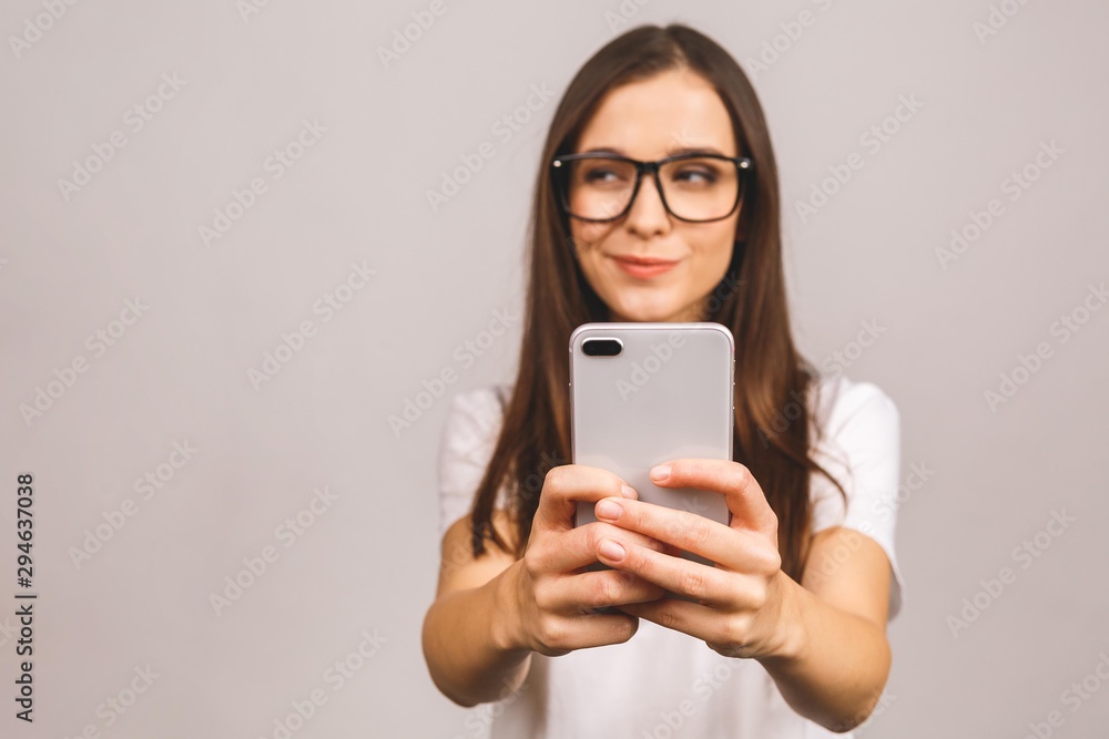Portrait of a happy young teenage girl dressed in casual using mobile phone isolated over gray background. Portrait of a happy young teenage girl dressed in casual using mobile phone isolated over gray background.
