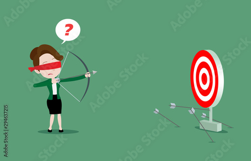 Blindfolded businesswoman is trying to use bow and arrow for archery but misses the target