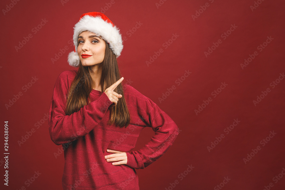 Christmas Santa hat woman portrait. Smiling amazed happy girl isolated against red background. Free copyspace for text. New year concept. Christmas Santa hat woman portrait. Smiling amazed happy girl isolated against red background. Free copyspace for text. New year concept.