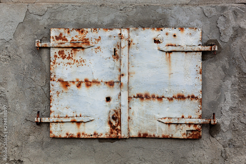 Old, rusty and weathered metal window coverings, closed shut on building exterior Old, rusty and weathered metal window coverings, closed shut on building exterior