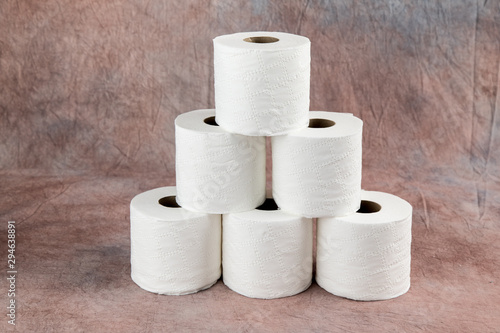 rolls oF soft toilet paper on a dusty pink cloth background