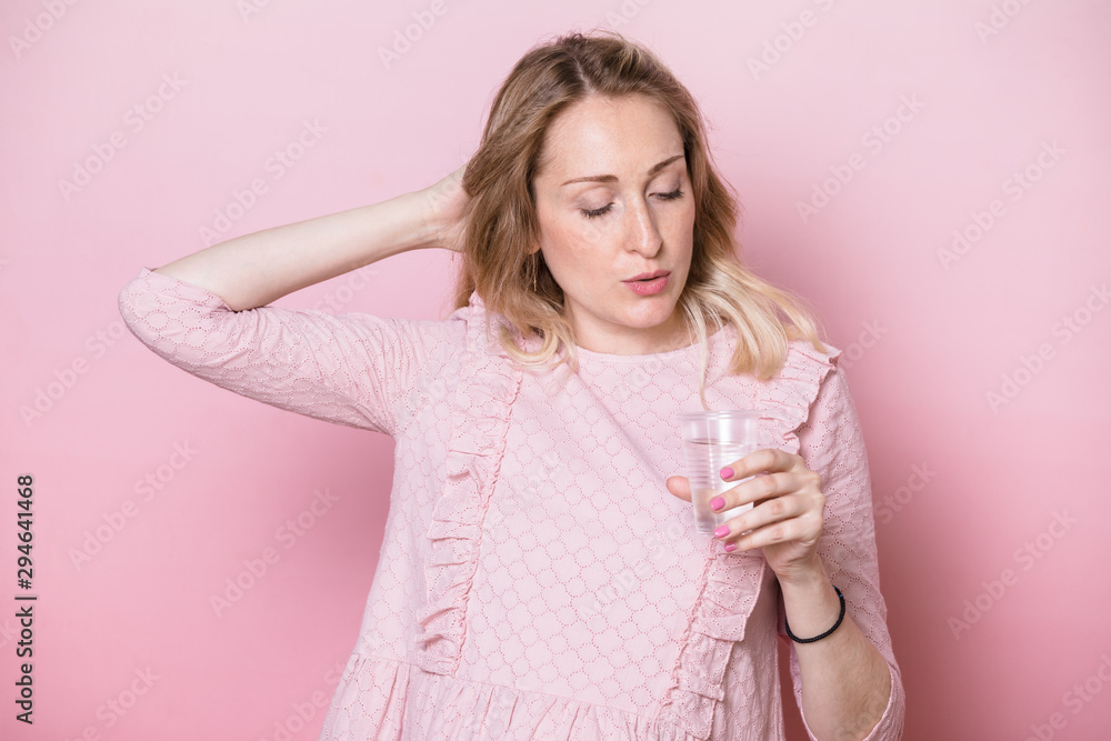 Pregnant woman holding plastic cup of water studio shot on pink background Pregnant woman holding plastic cup of water studio shot on pink background