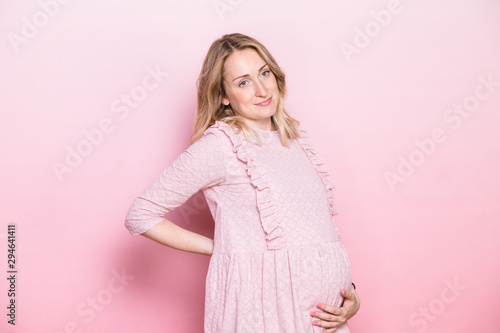 Pregnant woman holding her belly studio shot on pink background