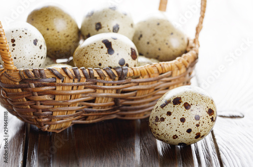 Fresh organic quail eggs in small wicker basket on rustic kitchen table. Space for text