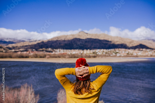 young caucasian woman on the mountain in sunny day. Beautiful lake background view. Nature concept. back view