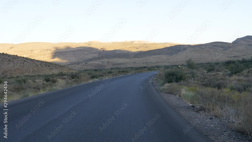 Drive Plate-Unlined blacktop road in shadow at sundown with sunlight still on the distant hills in the Nevada desert west of Las Vegas-Forward view Drive Plate-Unlined blacktop road in shadow at sundown with sunlight still on the distant hills in the Nevada desert west of Las Vegas-Forward view