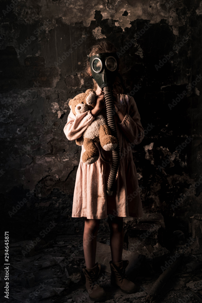 kid in gas mask standing and holding teddy bear, post apocalyptic concept