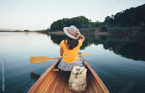 Fotografie Rear view of travel girl with hat paddling the canoe on lake