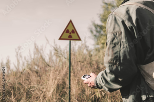 cropped view of man holding radiometer near toxic symbol, post apocalyptic concept