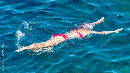 A girl swims in the blue water of the sea