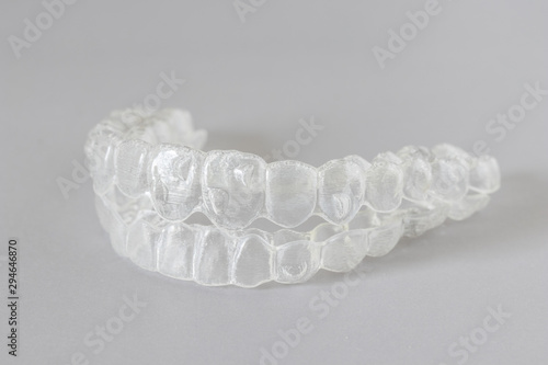 Close up view of invisalign braces or invisible retainers on grey background, new orthodontic equipment