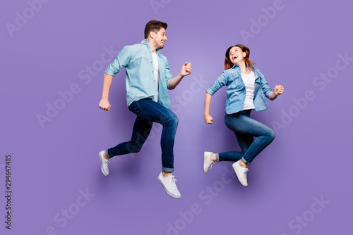Full body photo of fun romantic funny brown hair redhair spouses jump run enjoy weekends holidays wear modern spring outfit white sneakers isolated over violet purple color background
