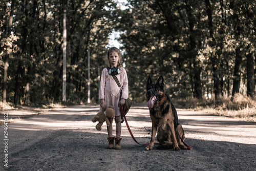 upset kid standing on road with teddy bear and german shepherd dog, post apocalyptic concept © LIGHTFIELD STUDIOS