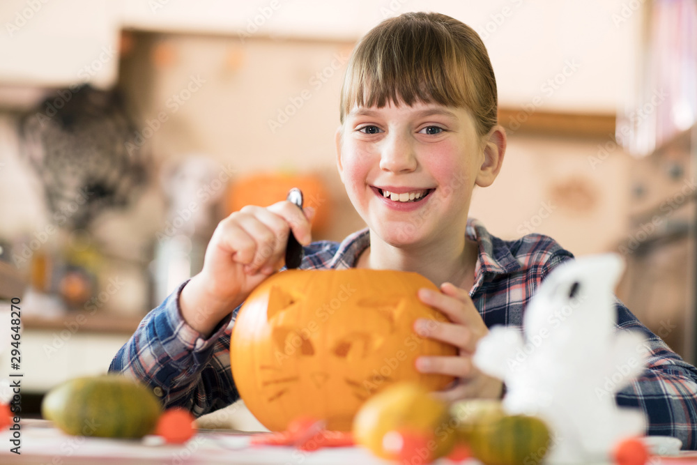 Fototapeta premium Portrait Of Girl Carving Halloween Lantern From Pumpkin At Home