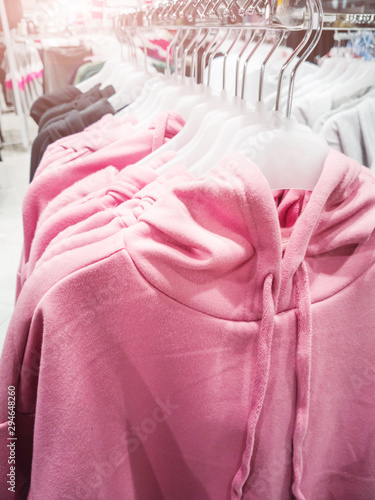 Warm pink hoodies hang on hangers in a store. The concept of assortment, discounts, fashion, winter collection.