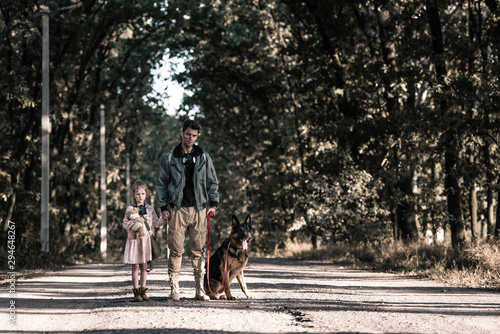man holding hands with child near german shepherd dog, post apocalyptic concept