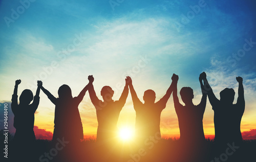 Silhouette of group business team making high hands over head in sunset sky photo
