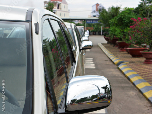 Taxi cars are lined up. View of the rear view mirrors. Beautiful flowers in flower pots are lined up to the right. Cars are located at the airport in Vietnamese on the island of Phu Quoc.