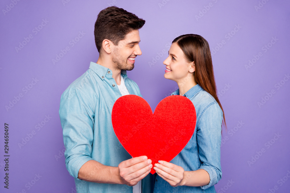 Profile side photo of romantic two students married couple hold paper card heart sign of feelings gift for 14-february honeymoon wear denim jeans outfit isolated over purple violet color background Profile side photo of romantic two students married couple hold paper card heart sign of feelings gift for 14-february honeymoon wear denim jeans outfit isolated over purple violet color background