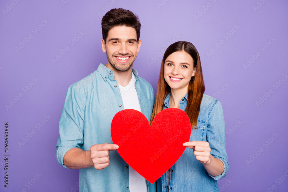 Portrait of romantic two married people couple hold paper card red heart gift for valentine day enjoy date wear stylish trendy outfit isolated over purple violet color background