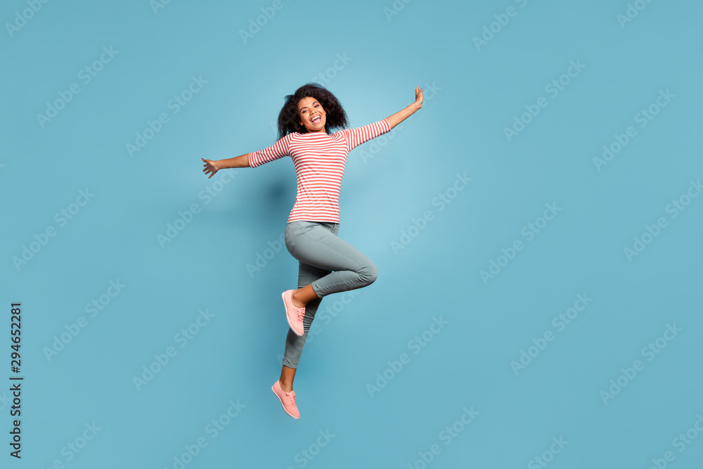 Full length body size photo of cheerful cute charming nice funky girlfriend jumping up with hands raised wearing trousers pants isolated over pastel color background