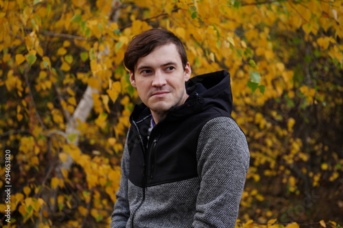 Portrait of a young handsome man in casual clothes against the yellowed trees in the autumn forest. © Anton Dios