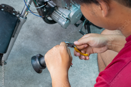 Mechanic man fix or repair motorcycle in garage Cutting electric wires with cutting pliers. Repair or maintanance concept.