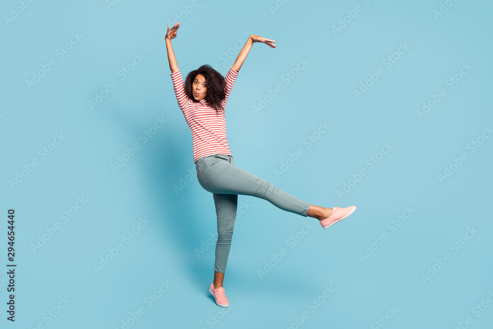 Fototapeta Full length photo of funny dark skin wavy lady making crazy facial expressions raising hands up foolish mood wear casual clothes isolated pastel blue color background
