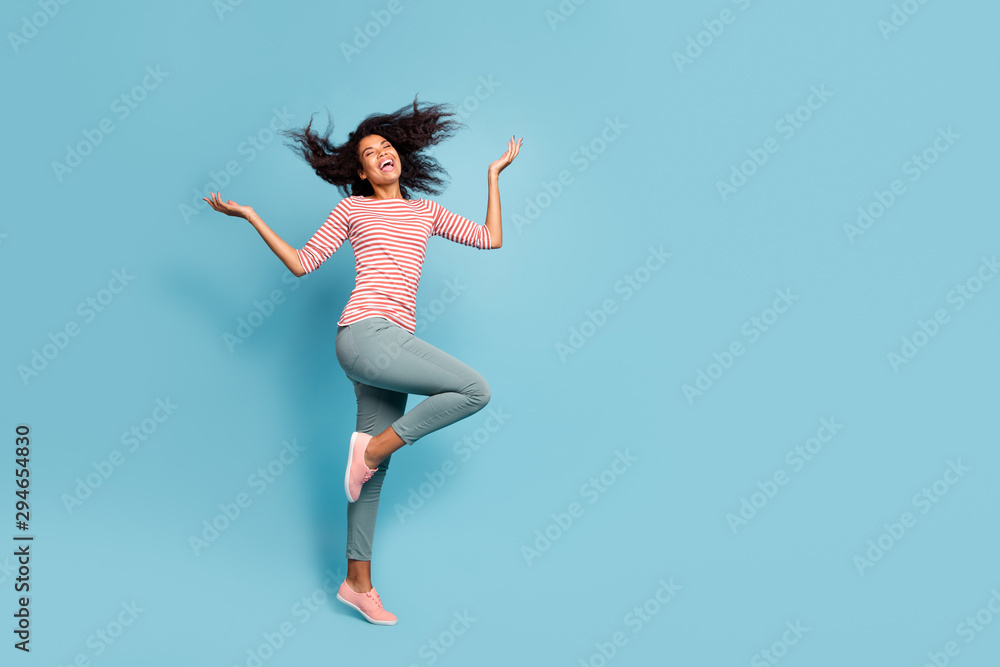Full body photo of amazing funny dark skin lady walking street sunny day enjoy spring breeze playing her hair curls wear casual clothes isolated pastel blue color background - obrazy, fototapety, plakaty 
