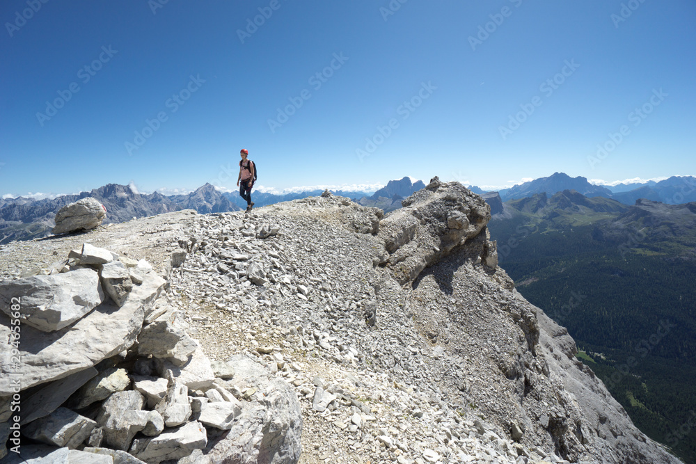 woman climber hiking along a rocky summit ridge in the Dolomites of Italy