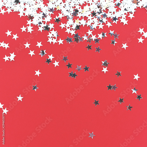 Silver stars confetti on a red background.