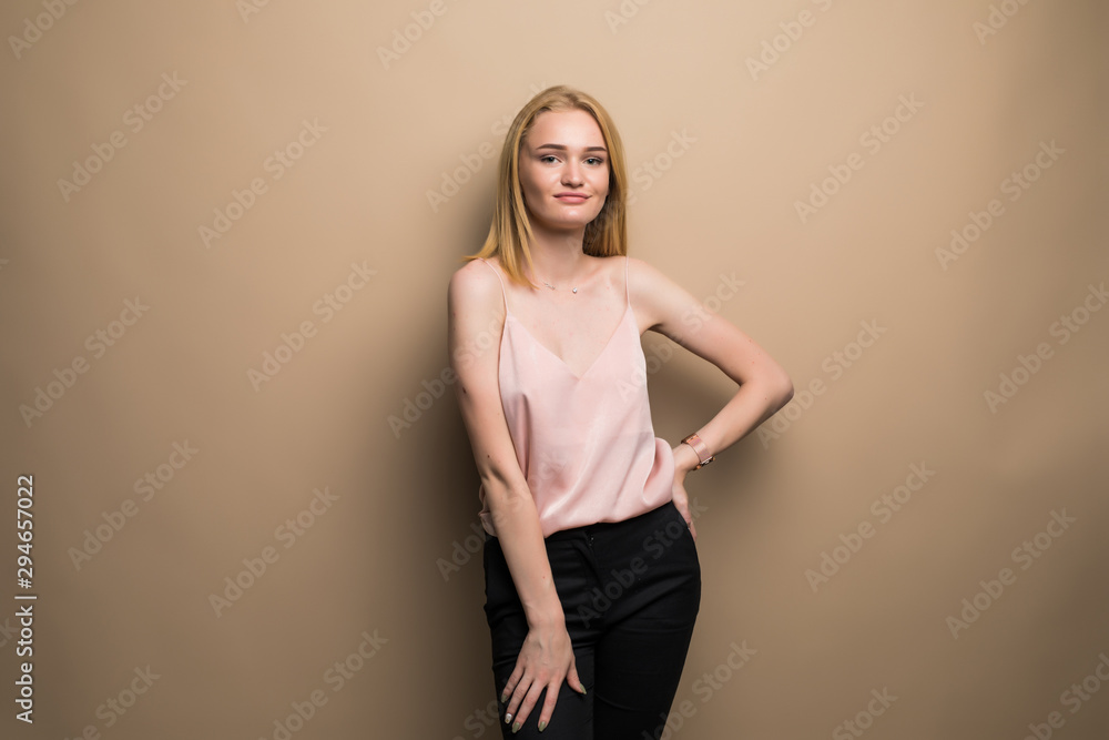 Charming woman with curly hair standing with hands folded, looking at camera, isolated over beige background Charming woman with curly hair standing with hands folded, looking at camera, isolated over beige background