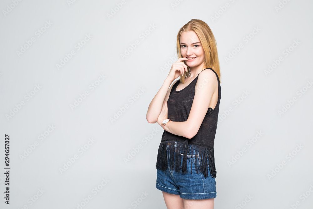 Portrait of a happy smiling beautiful woman posing with hand in hair against gray background Portrait of a happy smiling beautiful woman posing with hand in hair against gray background