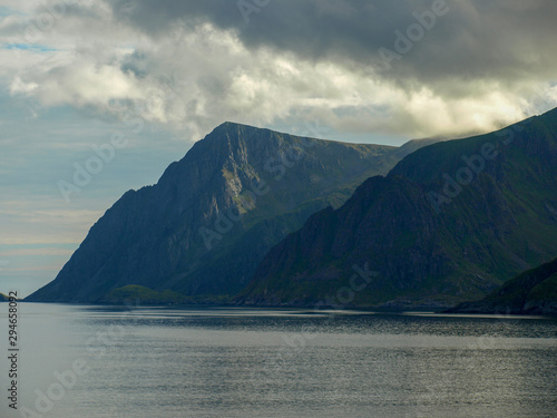 landscape with beautiful green overgrown rocks at the fjord, beautiful sea water and glare