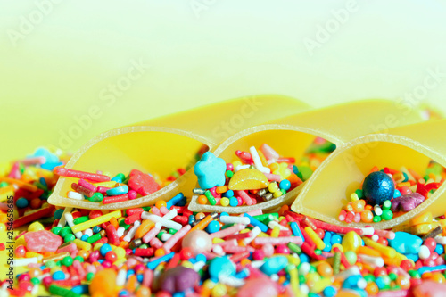 Abstract food background. Durum wheat pasta and colorful candies over yellow background. Incompatible products concept.