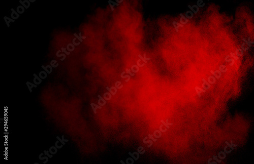 Red powder explosion cloud on black background. Freeze motion of red color dust  particles splashing.