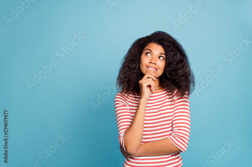 Photo of serious confused interested black millennial trying to remember important information biting her lips touching chin with hands isolated over blue color vivid background photo