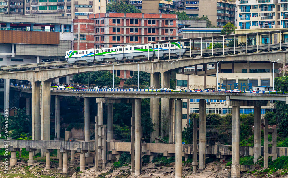 China. Monorail in the Chinese city of Chongqing, Yuzhong district. Metro train rides on a monorail. Transport, traffic flow, city blocks. Trees and bushes on the banks of the Jialing River.