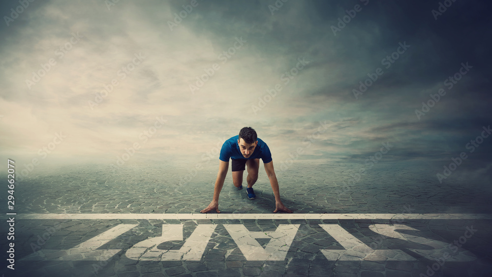 Determined man runner standing in running position, at the start line,  looking ahead confident. Young guy sprinter ready for new challenges.  Winner behaviour and motivation concept. Stock Photo | Adobe Stock