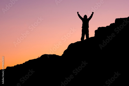 on the mountain, the silhouette of a man with his hands up against the dark sky