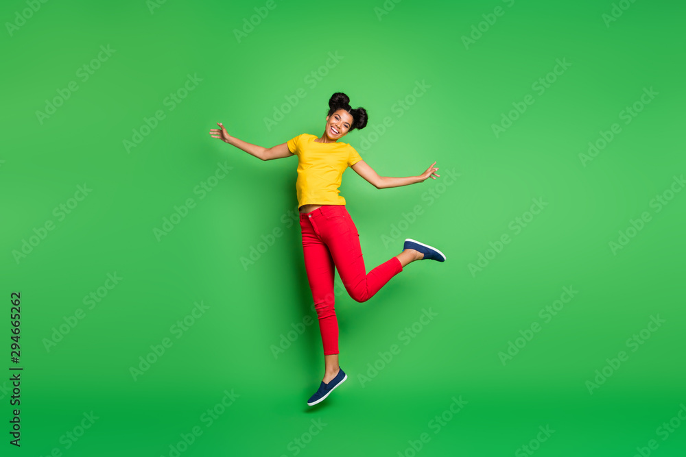 Full length photo of pretty dark skin lady jumping high supporting team at competitions wear casual yellow t-shirt red pants isolated green background