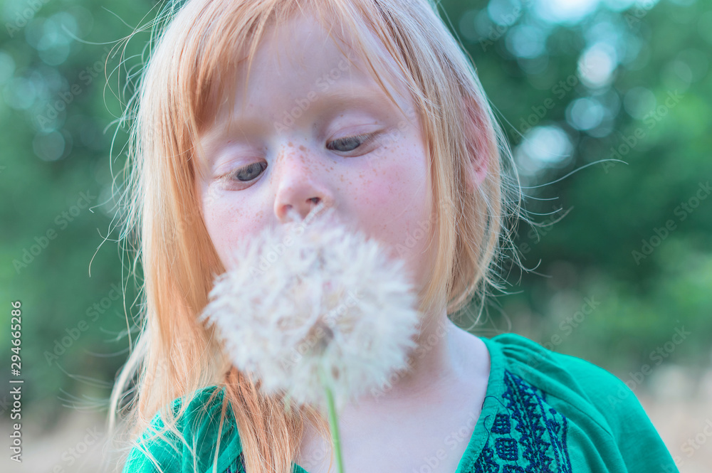 Portrait of a beautiful red-haired girl with freckles and closed eyes is blow to dandaleon Portrait of a beautiful red-haired girl with freckles and closed eyes is blow to dandaleon