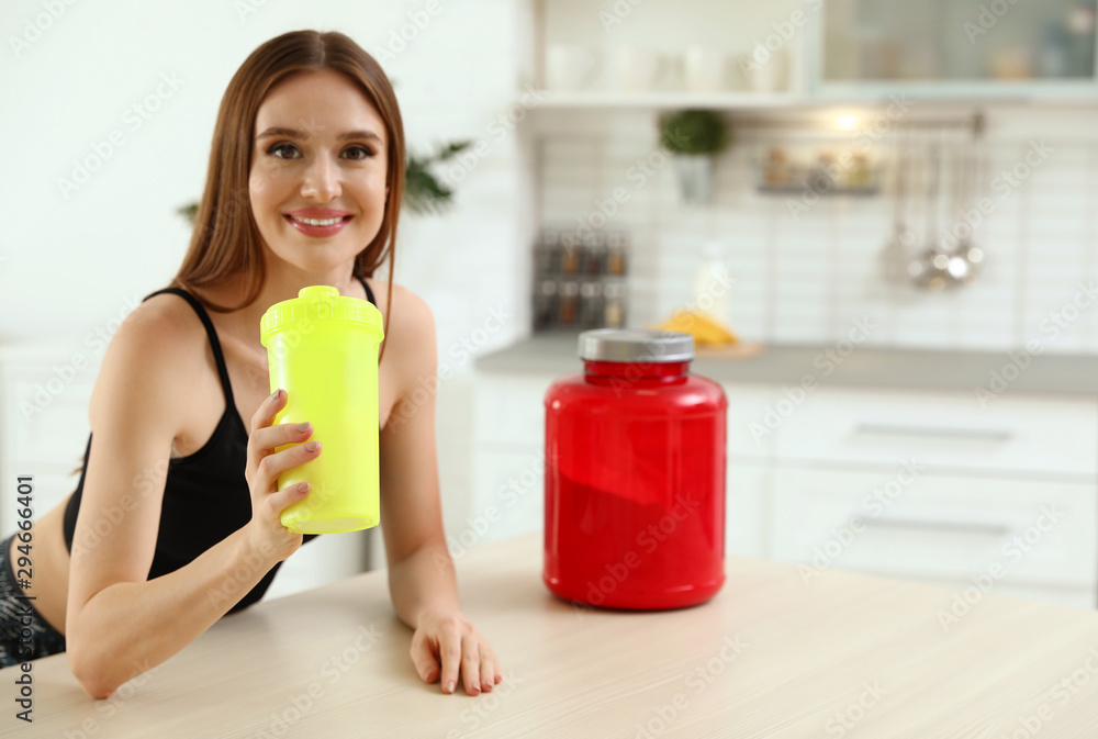 Young woman drinking protein shake at table indoors Young woman drinking protein shake at table indoors