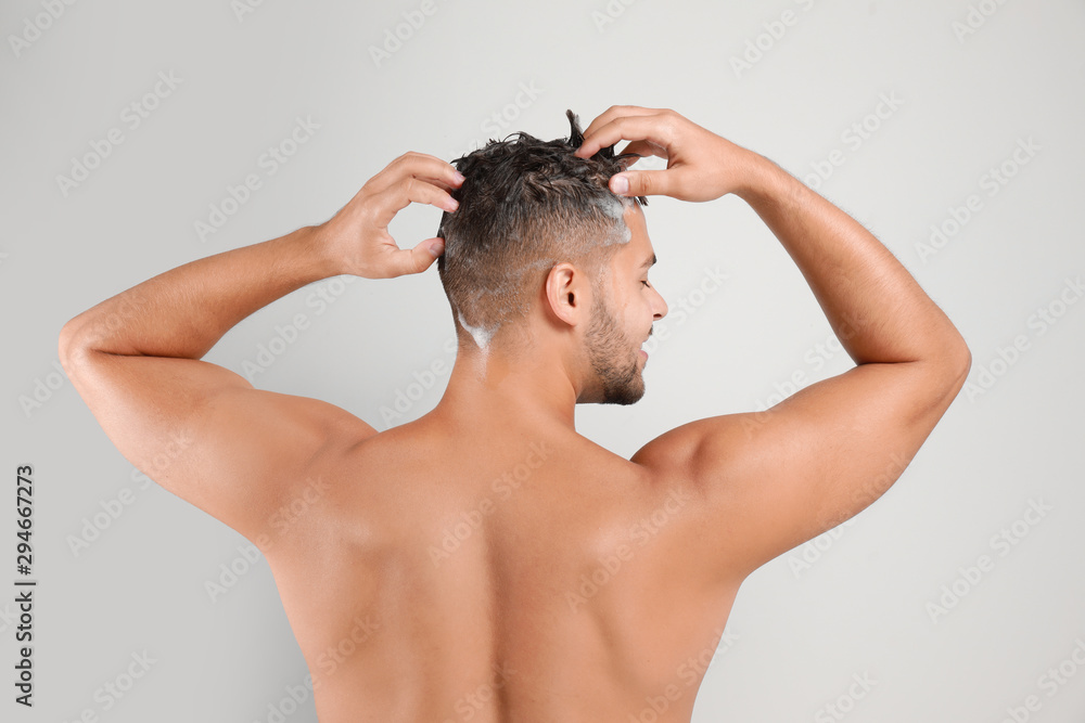 Young man washing hair on white background, back view Young man washing hair on white background, back view