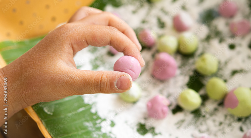 Closeup hand kid shows natural colorful rice flour ball with various balls and flour powder on banana leaf. Closeup hand kid shows natural colorful rice flour ball with various balls and flour powder on banana leaf.
